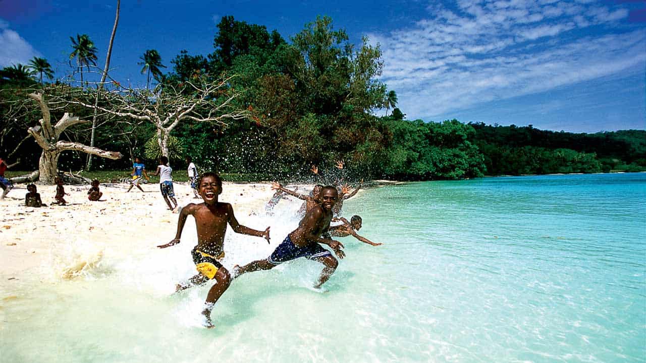 Vanuatu — Happiest People in the Pacific, Melanesian Culture and Family Values — 人民幸福与文化魅力 Children playing on a tropical beach in Vanuatu, illustrating the nation’s happy Melanesian communities, strong family values, and relaxed island lifestyle — 瓦努阿图幸福生活